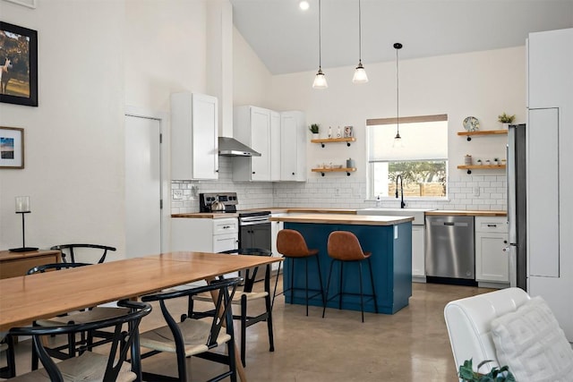 kitchen with open shelves, stainless steel appliances, wood counters, and a sink