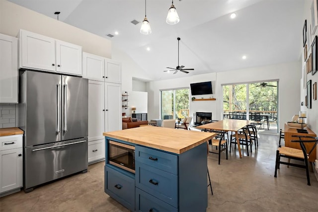 kitchen with a ceiling fan, appliances with stainless steel finishes, finished concrete flooring, and butcher block counters