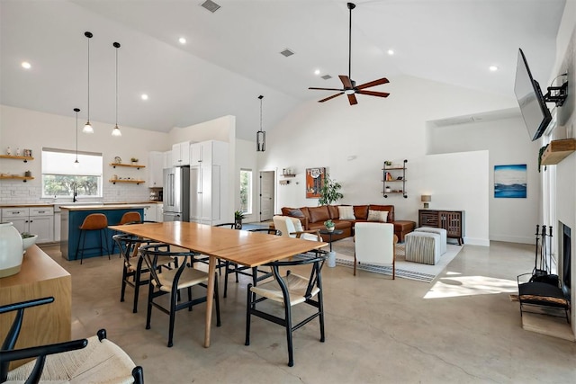 dining space featuring visible vents, ceiling fan, concrete flooring, recessed lighting, and high vaulted ceiling