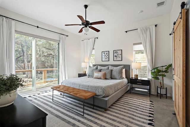 bedroom featuring visible vents, multiple windows, a barn door, and finished concrete floors