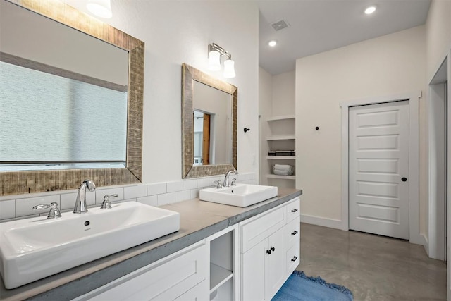 bathroom with double vanity, finished concrete flooring, visible vents, and a sink