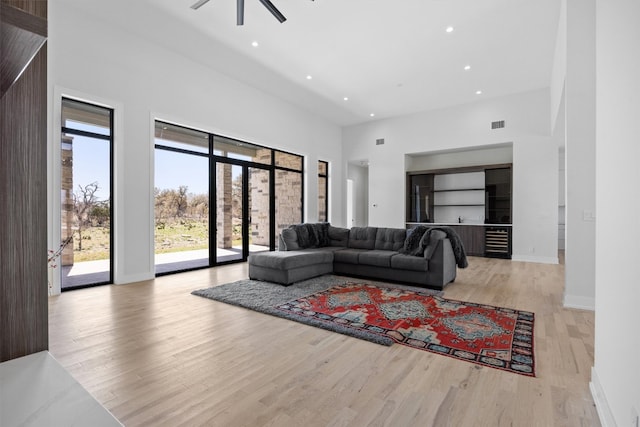 living room with light wood-type flooring, recessed lighting, a high ceiling, baseboards, and ceiling fan