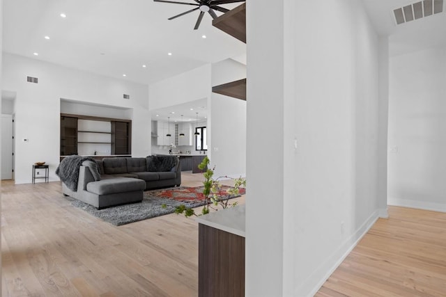 living room with a ceiling fan, light wood-style floors, and visible vents