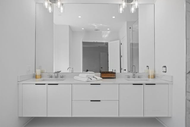 bathroom with double vanity, an enclosed shower, recessed lighting, and a sink