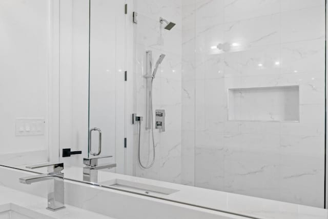 full bath featuring a marble finish shower and a sink