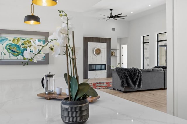 living room with wood finished floors, a ceiling fan, a high ceiling, a fireplace, and recessed lighting