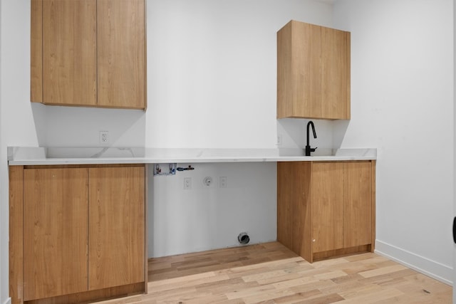 laundry area with a sink, cabinet space, light wood-style floors, and washer hookup