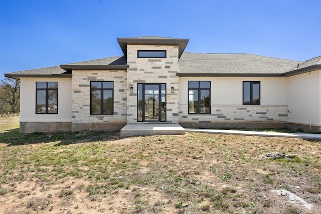 view of front facade featuring stone siding and roof with shingles