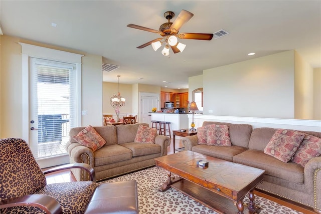 living area with visible vents and ceiling fan with notable chandelier