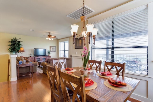 dining room with visible vents, ceiling fan with notable chandelier, baseboards, and hardwood / wood-style floors