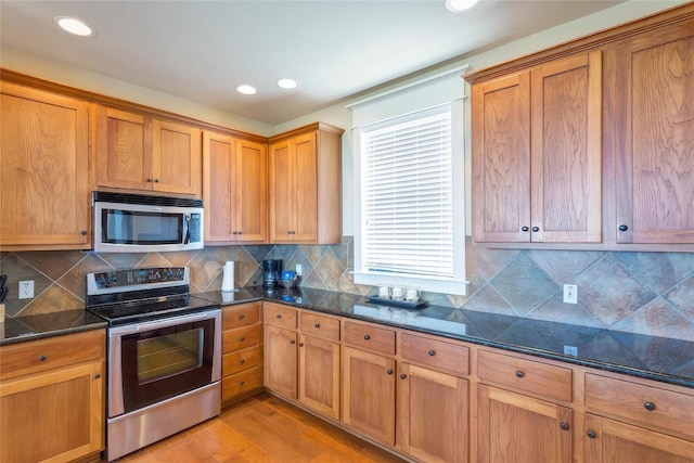 kitchen with stainless steel appliances, brown cabinetry, and light wood finished floors