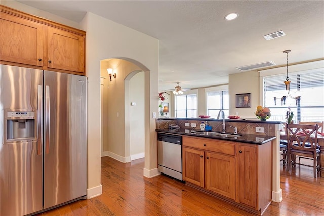 kitchen featuring visible vents, appliances with stainless steel finishes, a peninsula, arched walkways, and a sink