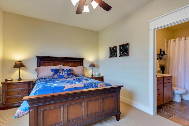 bedroom with light colored carpet, a ceiling fan, baseboards, and connected bathroom