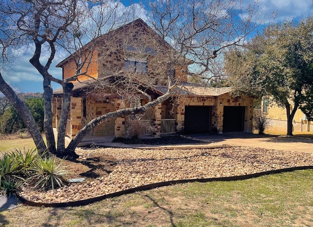 view of front of property featuring stone siding, driveway, and a garage