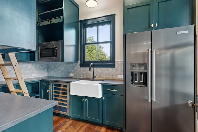 kitchen featuring a sink, wine cooler, appliances with stainless steel finishes, green cabinetry, and decorative backsplash