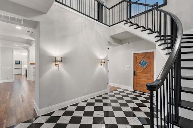 foyer with stairway, a high ceiling, baseboards, and visible vents