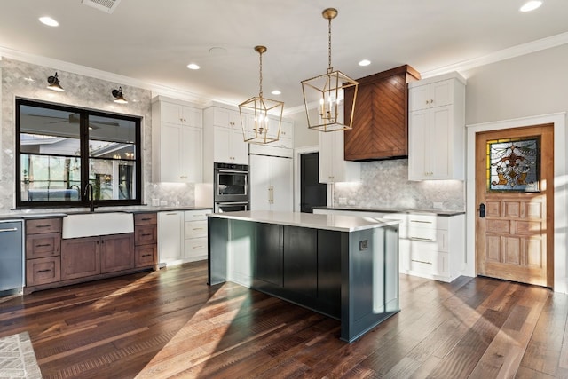 kitchen featuring crown molding, double wall oven, a center island, and a sink