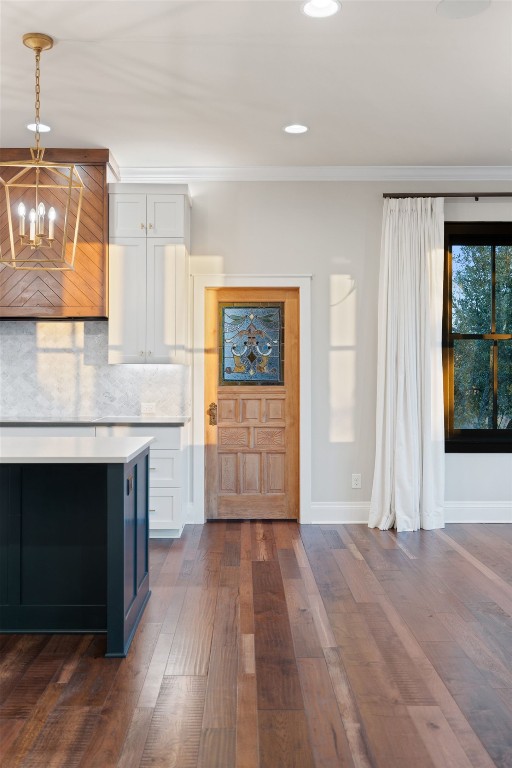 kitchen with dark wood finished floors, an inviting chandelier, white cabinets, and tasteful backsplash