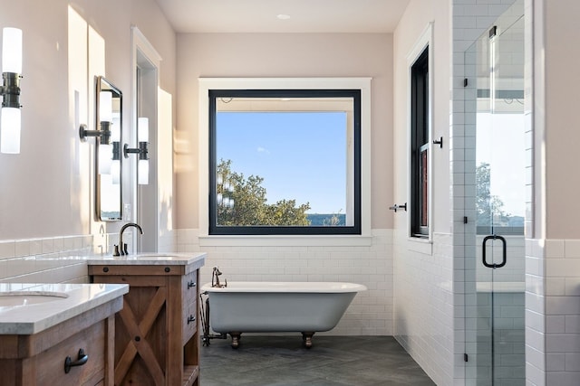 full bath featuring a sink, tile walls, two vanities, and a shower stall