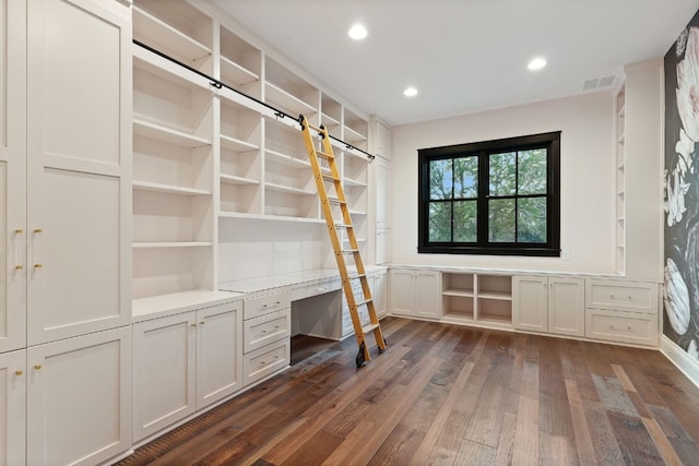 unfurnished office with visible vents, built in desk, recessed lighting, a barn door, and dark wood-style flooring