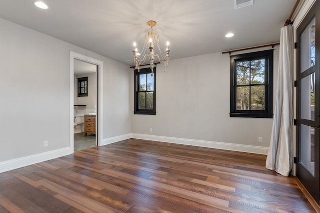 empty room featuring an inviting chandelier, recessed lighting, baseboards, and dark wood-style flooring