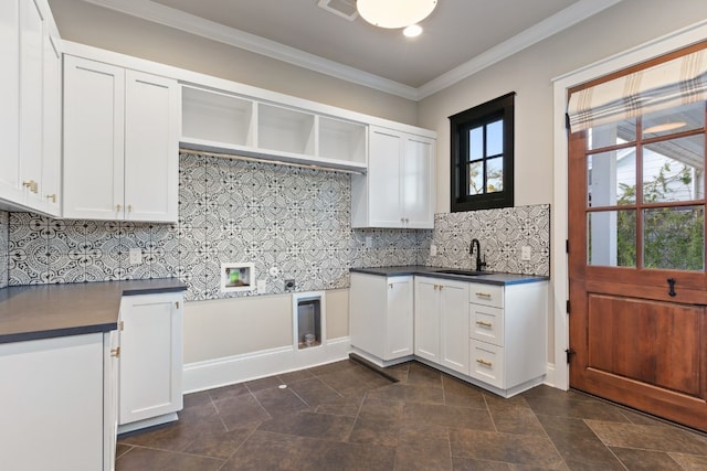 kitchen featuring a sink, dark countertops, ornamental molding, and white cabinets