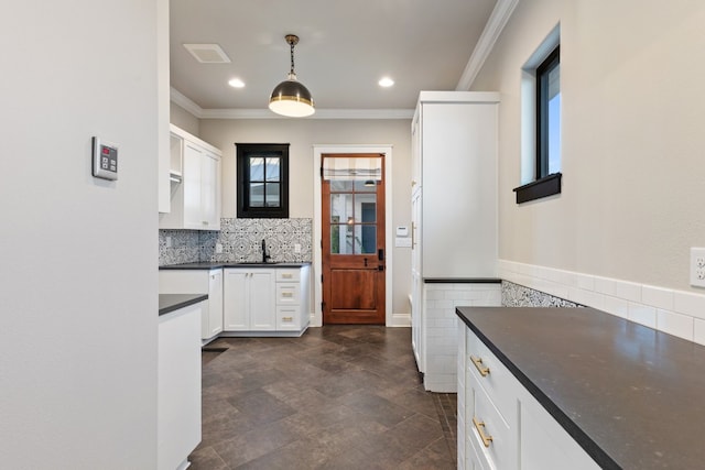 kitchen featuring dark countertops, white cabinetry, and crown molding