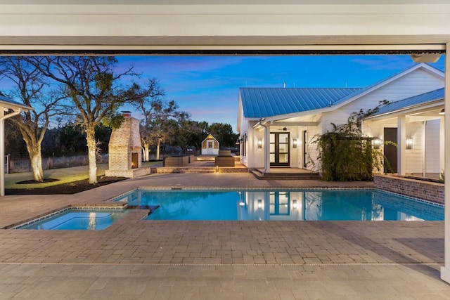 view of pool featuring a patio, a warm lit fireplace, and a pool with connected hot tub