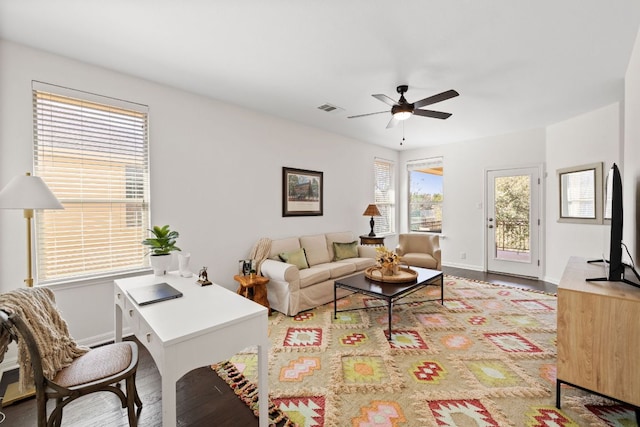 living area with wood finished floors, a ceiling fan, visible vents, and baseboards