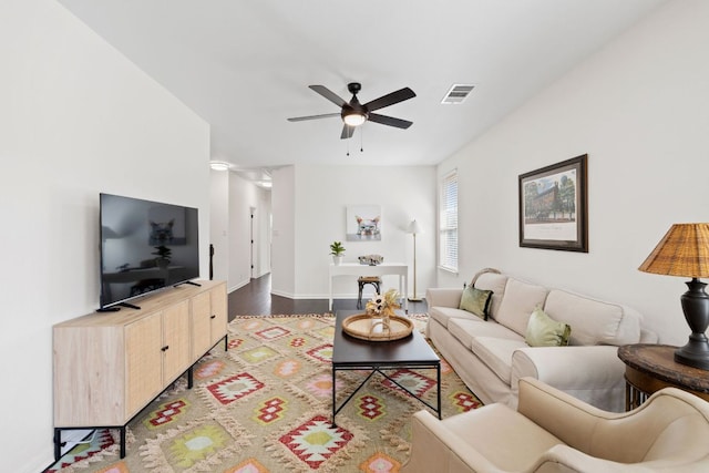 living room with wood finished floors, a ceiling fan, visible vents, and baseboards