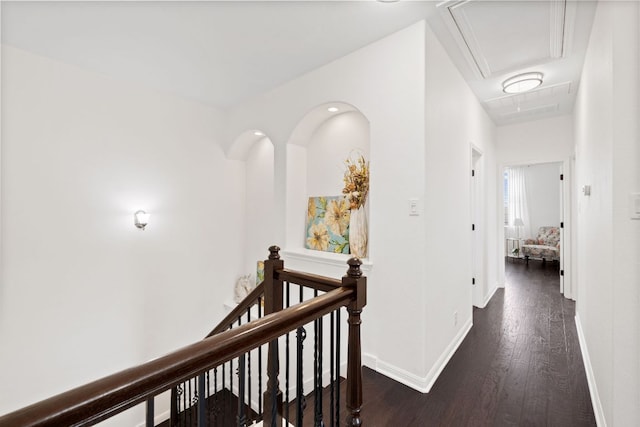 hall with baseboards, an upstairs landing, attic access, and wood finished floors