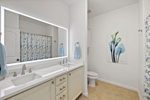 bathroom with a sink, baseboards, toilet, and double vanity