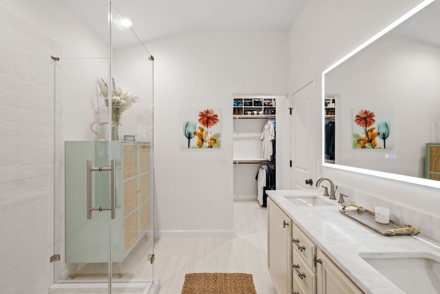 full bath featuring a spacious closet, baseboards, double vanity, a stall shower, and a sink