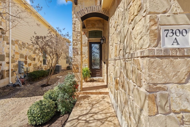 entrance to property with stone siding and cooling unit