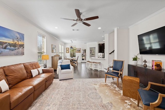 living area with visible vents, light wood-style flooring, recessed lighting, ceiling fan, and crown molding