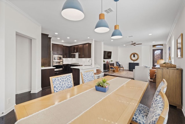 dining space with visible vents, crown molding, dark wood-type flooring, and a ceiling fan