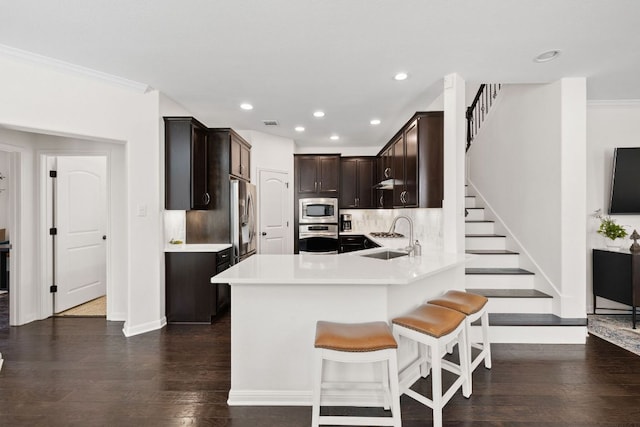 kitchen with dark wood-type flooring, a sink, appliances with stainless steel finishes, light countertops, and dark brown cabinets