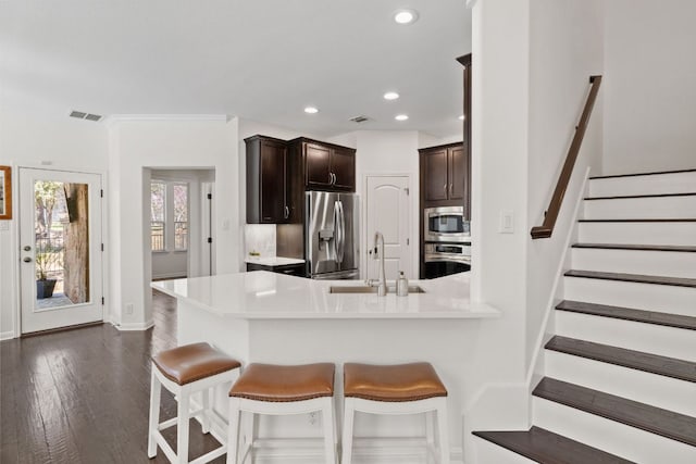 kitchen with visible vents, a sink, stainless steel appliances, light countertops, and dark brown cabinets