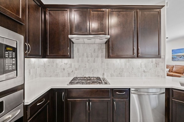 kitchen with decorative backsplash, dark brown cabinetry, light countertops, appliances with stainless steel finishes, and under cabinet range hood