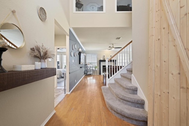 entryway featuring stairway, a ceiling fan, visible vents, baseboards, and light wood-style flooring