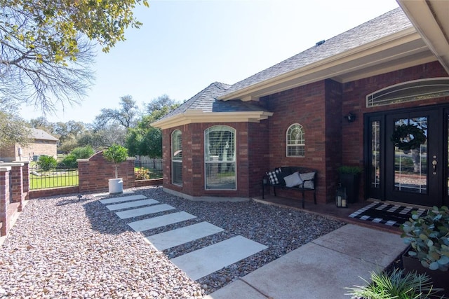 entrance to property featuring covered porch, a gate, fence, and brick siding