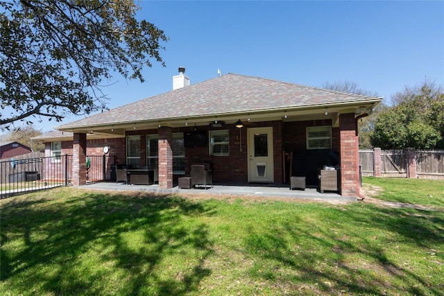 back of property with fence, roof with shingles, a lawn, a chimney, and a patio area