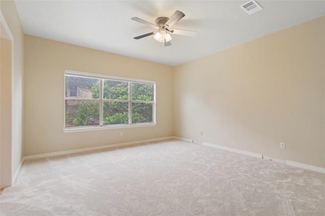 empty room featuring visible vents, light colored carpet, baseboards, and a ceiling fan