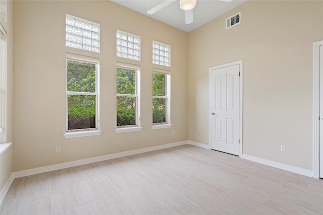 spare room with visible vents, baseboards, a high ceiling, and ceiling fan