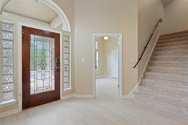 foyer entrance featuring stairs, baseboards, and a towering ceiling