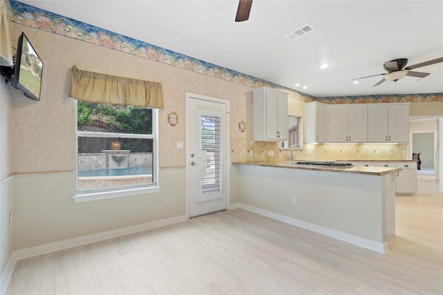 kitchen with baseboards, visible vents, white cabinetry, and a ceiling fan