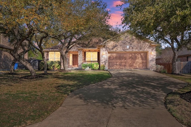 ranch-style house featuring driveway, stone siding, fence, a front yard, and an attached garage