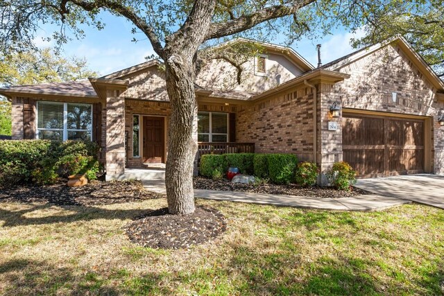 view of front of house featuring a front yard, brick siding, a garage, and driveway