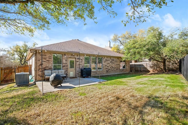 rear view of house with cooling unit, a yard, a fenced backyard, a patio area, and brick siding