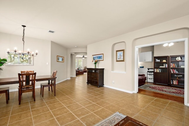 dining area with tile patterned flooring, visible vents, baseboards, an inviting chandelier, and arched walkways